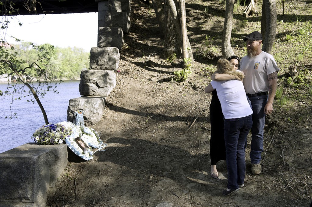 Helena Gagliano-McFarland gets a hug from Kelly Henry near where McFarland's 5-year-old son, Valerio, fell into the Androscoggin River in Auburn. McFarland's husband and Valerio's father, Jason, is at right. Henry said she became friends with the family as the three-week search for Valerio's body played out.