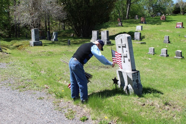 Bud Smith, 92, of Farmingdale, places American flags on Monday on the graves of veterans for the town of Farmingdale, many of whom he served with during World War II.