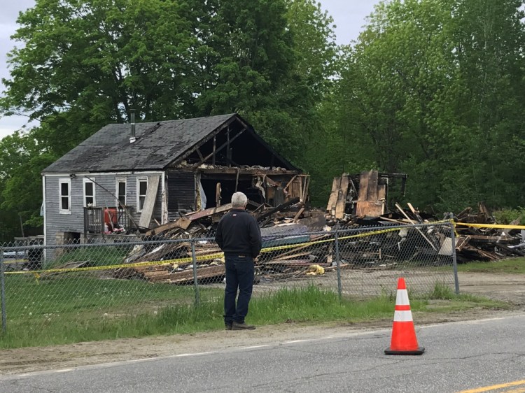 Carl Bagley, who has lived on Belgrade Road in Manchester for 34 years, surveys the damage that an early morning fire did to the home of one of his neighbors.