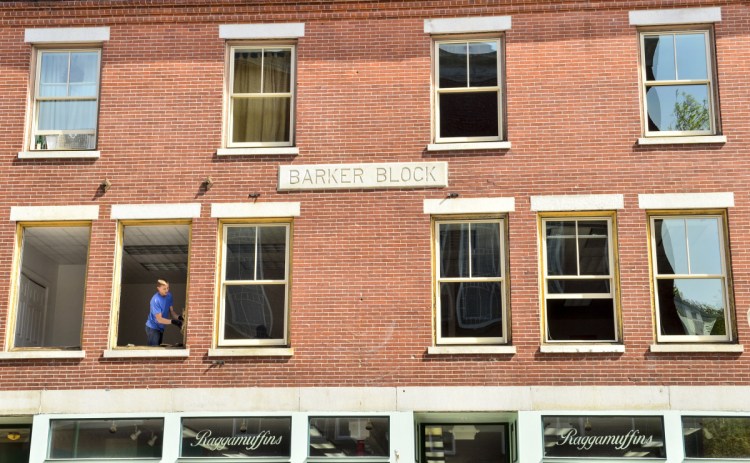 Kaleb Burbank, of Jacob's Glass, tears out the frames of old windows to install new Pella replacement windows in second floor office about Ragamuffin's on May 16 along the one way section of Water Street in downtown Gardiner.