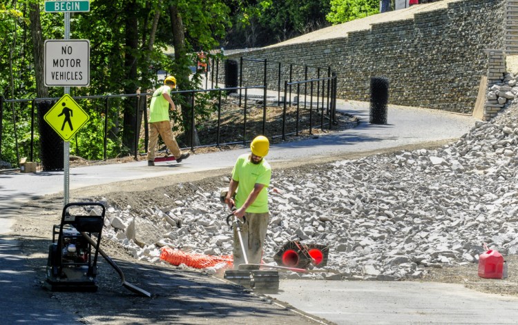 Josh Billings, left, and John Smith Cross Excavation, sweep the newest section of the Kennebec River Rail Trail on Tuesday in Augusta. The last quarter-mile of the trail leading from Augusta Waterfront park on Front Street to the base of Memorial Bridge will be officially opened with a ceremonial ribbon cutting at noon on Wednesday.