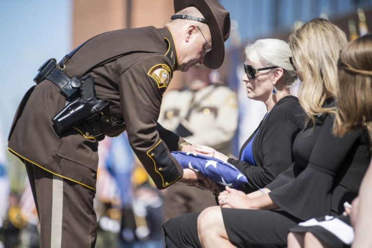 Somerset County Sheriff Dale Lancaster offers a folded American flag to Sheryl Cole, wife of Cpl. Eugene Cole, during funeral services at the Cross Insurance Center in Bangor on May 7.