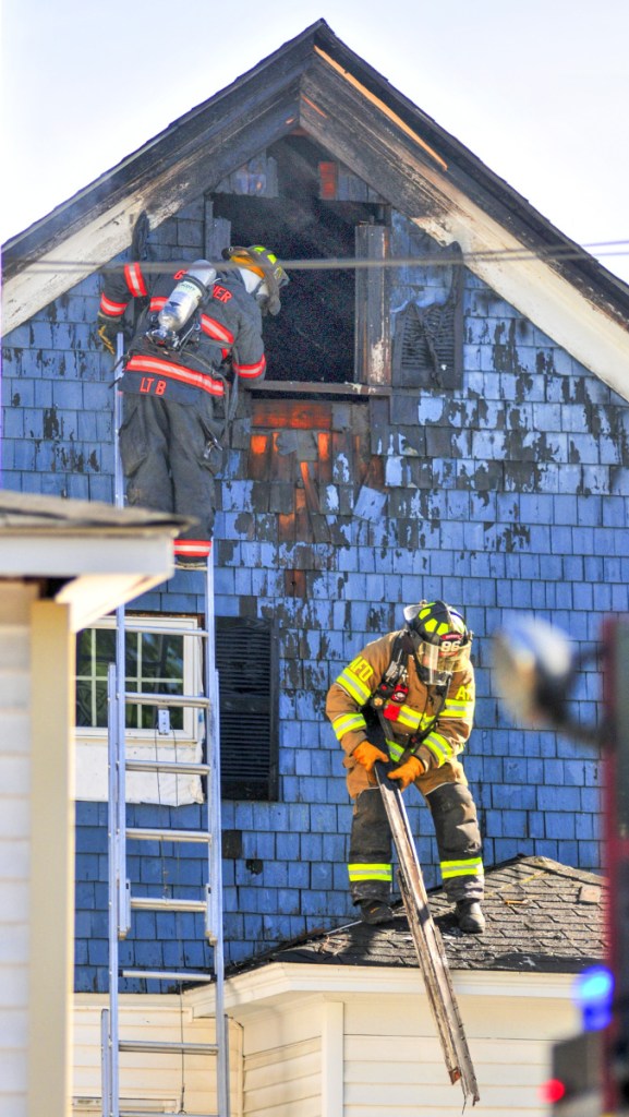 Firefighters pull off boards to expose fire underneath them at 79 Willow St. in Augusta on Wednesday.