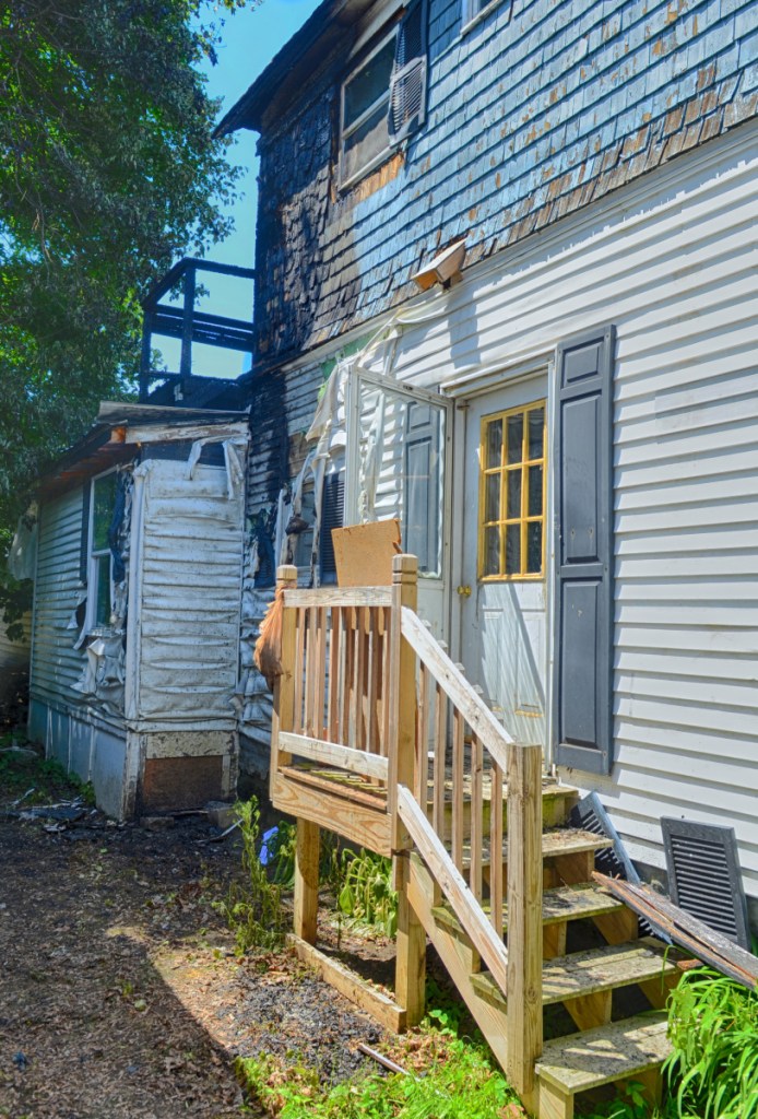Damage can be seen on the back deck of 79 Willow St. in Augusta, a day after a fire burned an apartment building there.