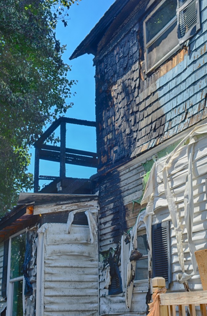 Damage can be seen on the back deck of 79 Willow St. in Augusta, a day after a fire burned an apartment building there.
