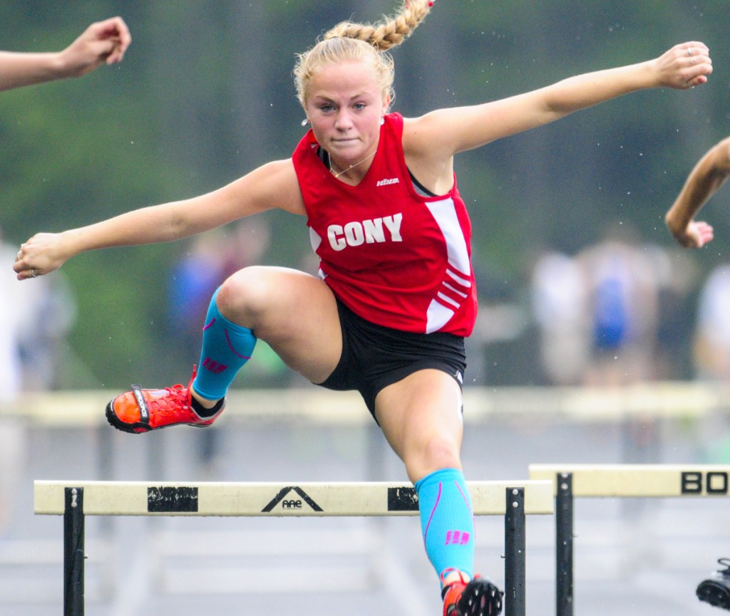 Cony's Anna Reny runs the 300-meter hurdles during a rainy Kennebec Valley Athletic Conference track and field championships last Saturday in Topsham.