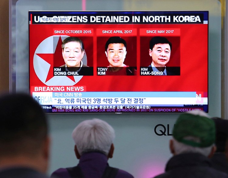 People watch a TV news report screen showing portraits of three Americans, Kim Dong Chul, left, Tony Kim and Kim Hak Song, right, detained in the North Korea, at the Seoul Railway Station in May.