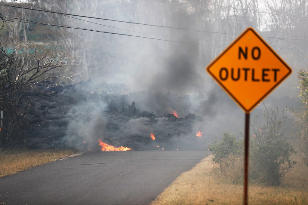 Lava crosses the road near Pohoiki Road, Friday near Pahoa, Hawaii. Hawaii residents covered their faces with masks after a volcano menacing the Big Island for weeks exploded, sending a mixture of pulverized rock, glass and crystal into the air in its strongest eruption of sandlike ash in days. 