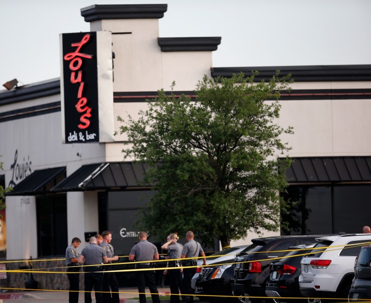 Police officers stand at the scene of a shooting on the east side of Lake Hefner in Oklahoma City, Thursday, May 24, 2018. A man armed with a pistol walked into Louie’s On The Lake restaurant at the dinner hour and opened fire, wounding two customers, before being shot dead by a handgun-carrying civilian in the parking lot, police said. (Sarah Phipps/The Oklahoman via AP)