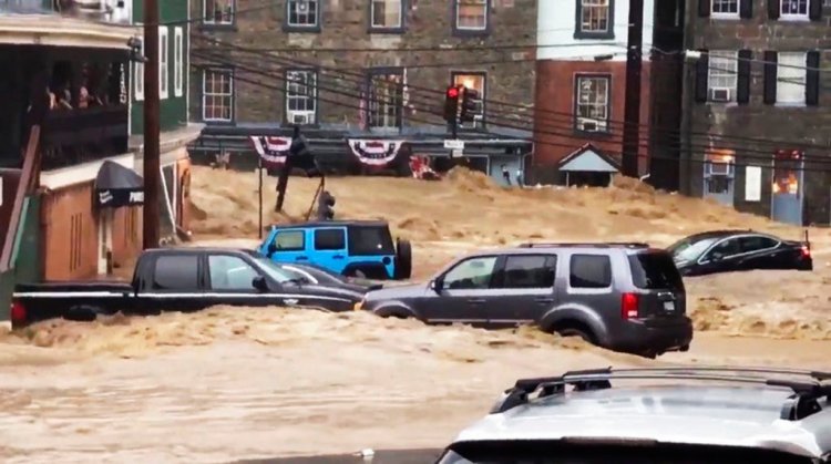 Water rushes through Main Street in Ellicott City, Md., Sunday.     Libby Solomon/The Baltimore Sun
