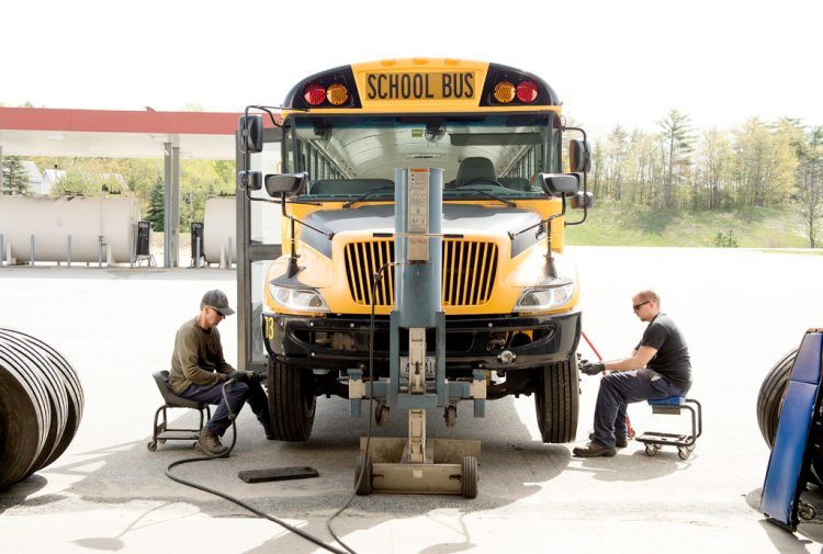 Bus mechanics Rob Sawyer, left, and his son Tyler Sawyer change the front two tires on school bus No.13 at the Regional School Unit 16 bus garage in Poland on Thursday. 