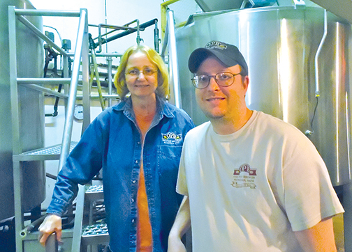 Nancy Chandler and son, Adam Chandler, in front of brewing tanks at Oak Pond Brewing Company in Skowhegan. Susan Varney photo
