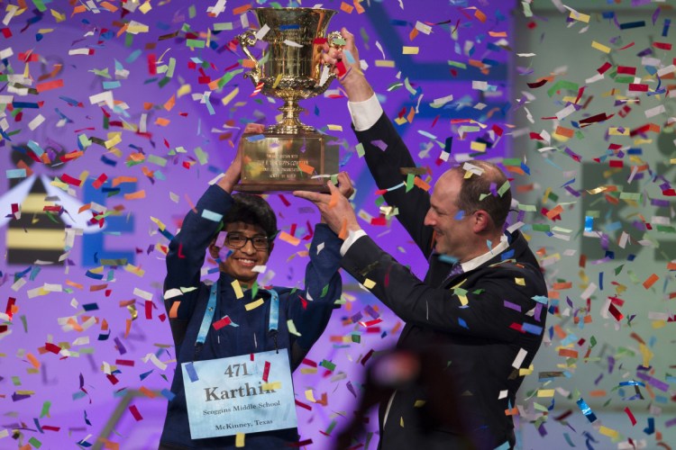 Karthik Nemmani, 14, from McKinney, Texas, is presented with the Scripps National Spelling Bee trophy by Adam Symson, president and CEO, E.W. Scripps Company.