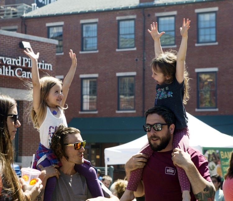 As Steven McCann of Bardstown, Ky., left, and his friend Joe Hughes of Ocean Park chat, their daughters Pearl McCann, 5, left, and Nixon Hughes, 6, listen to the music during the Old Port Festival in Portland on Sunday.