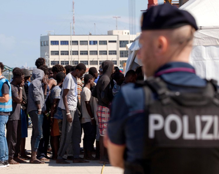 Migrants line up after disembarking at the Reggio Calabria harbor in southern Italy on Saturday. Meanwhile, an aid ship carrying 629 migrants rescued in the Mediterranean was waiting to learn where it can dock.