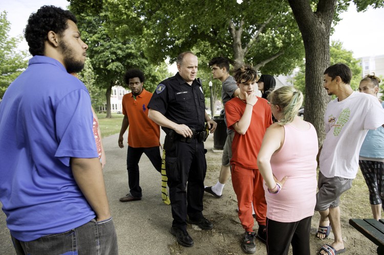 Lewiston police officer Tom Murphy talks with people Wednesday about a fight in Kennedy Park Tuesday night.