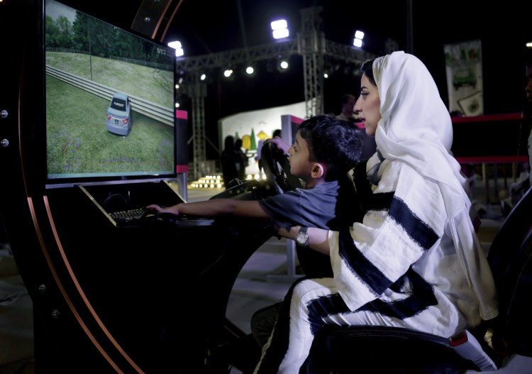 A woman tests a driving simulator with her son at a road safety event for female drivers on Friday at the Riyadh Park Mall in Saudi Arabia. Women may drive starting Sunday.
