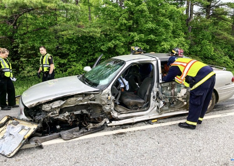 Law enforcement and rescue personnel inspect a mangled 2002 Buick LeSabre following a collision with a tractor-trailer Friday morning on Skowhegan Road in Fairfield. The vehicle's owner, John Hamlin, 64, of Cornville, was driving toward Fairfield when police say he got a flat tire, causing him to cross the center line and strike the tractor-trailer.