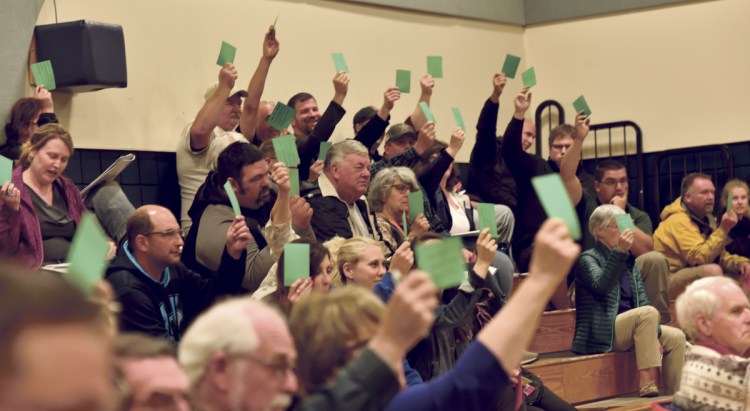 Vassalboro residents vote on an article Monday during the Vassalboro Town Meeting.