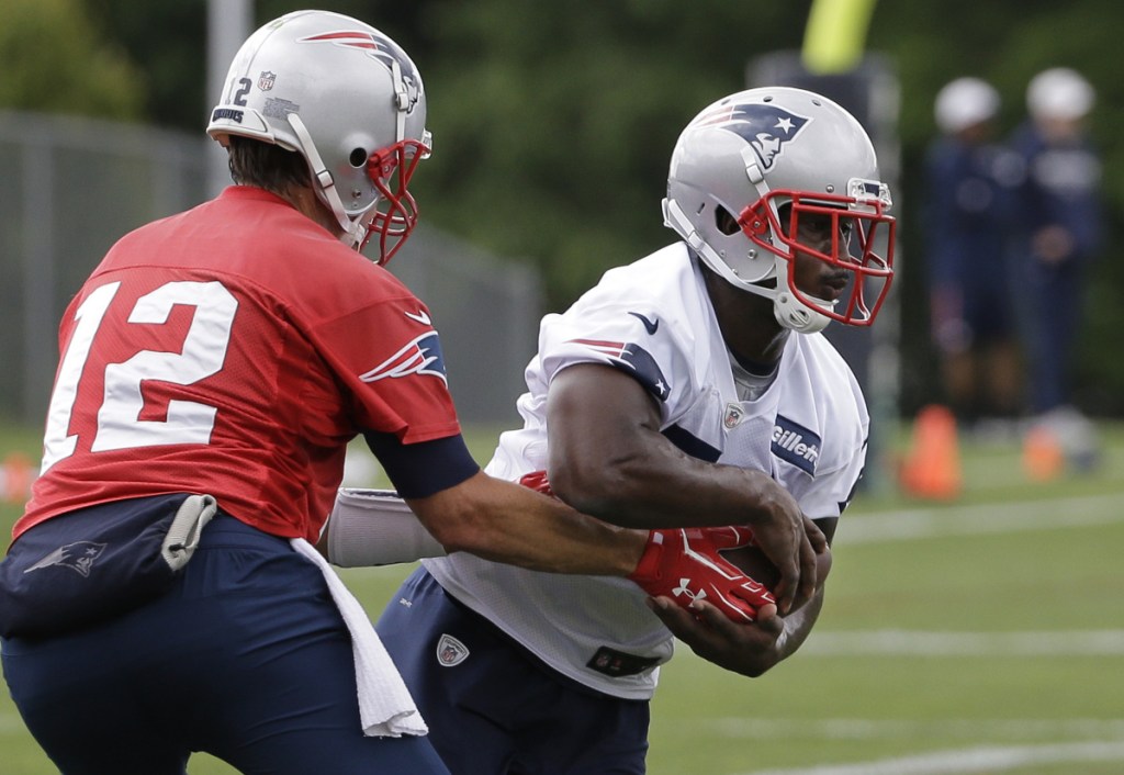 New England Patriots quarterback Tom Brady, left, hands off to rookie running back Sony Michel, right, during practice Tuesday in Foxborough, Massachusetts.