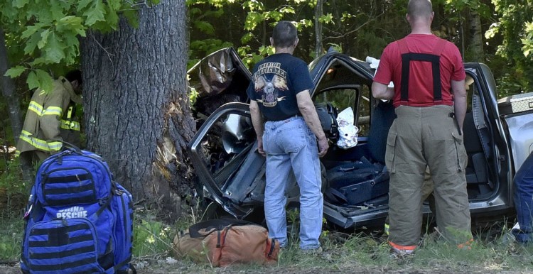 Firefighters survey the remains of a pickup truck destroyed Sunday after the driver veered off Route 32 in South China and slammed into a pine tree. The driver was extricated from the wreckage and a LifeFlight helicopter took him to the hospital.
