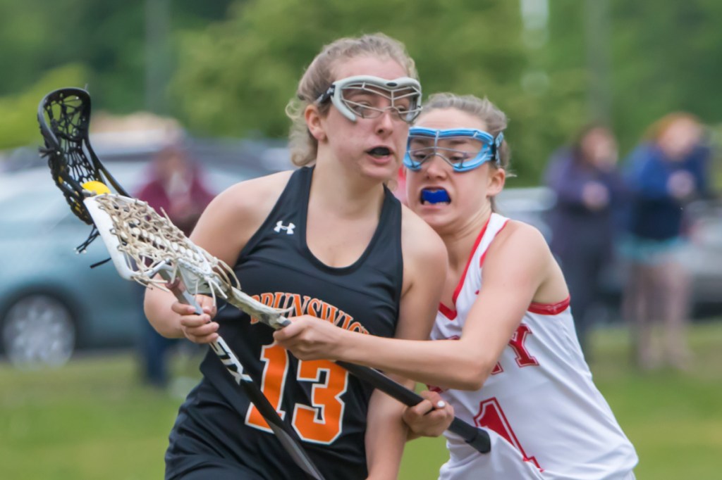 Brunswick's Lila Solberg, left, carries the ball while Cony defender Sierra Clark tries to knock her stick during a Class B lacrosse prelim Wednesday at Cony High School.