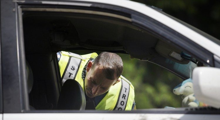 Maine State Police Sgt. Patrick Hood inspects a vehicle involved in a crash on Route 17 in Chelsea on Monday.