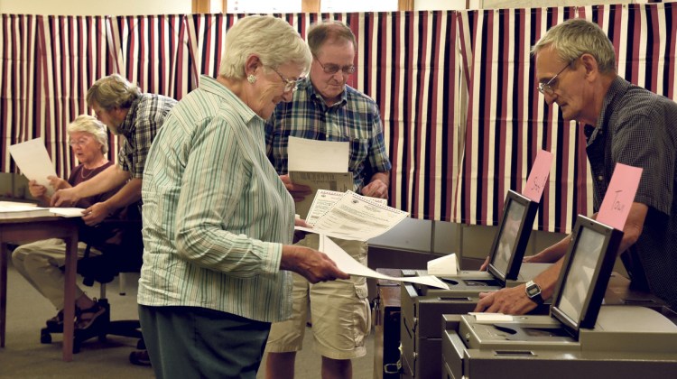 Election clerk Richard Irwin watches as Shirley Boone casts one of three ballots for local and state elections in Skowhegan on Tuesday. Town clerk Gail Pelotte commented on voter turnout by noon time saying, "It's been crazy busy so far today."