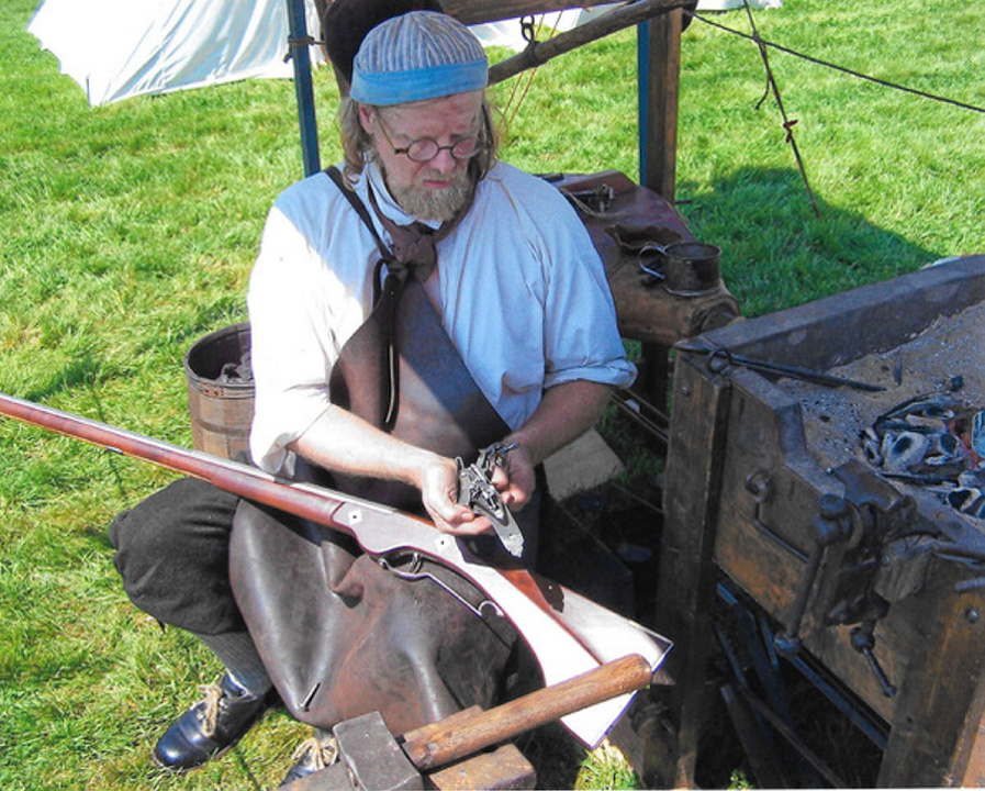 Blacksmith Jeff Miller works at his temporary forge. This type of forge was used by a blacksmith prior to establishing a permanent shop.