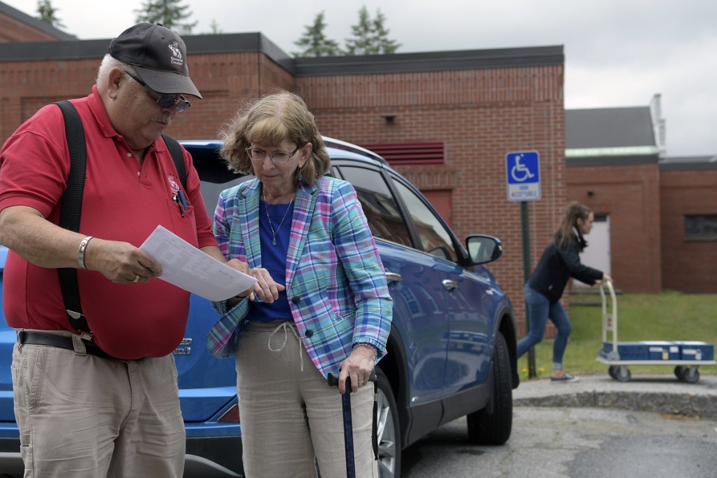 Deputy Secretary of State Julie Flynn confers with General Courier deliveryman Daniel Young on Thursday after he arrived in Augusta with ballots in preparation for the state's first ranked-choice voting tabulation process, which is scheduled to begin today. The ballots, at right, were carted into a state office building.