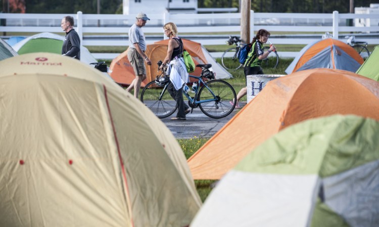 Cyclists walk to their tents in September at the Skowhegan Fairgrounds on the night before the start of the annual BikeMaine cycling trek.