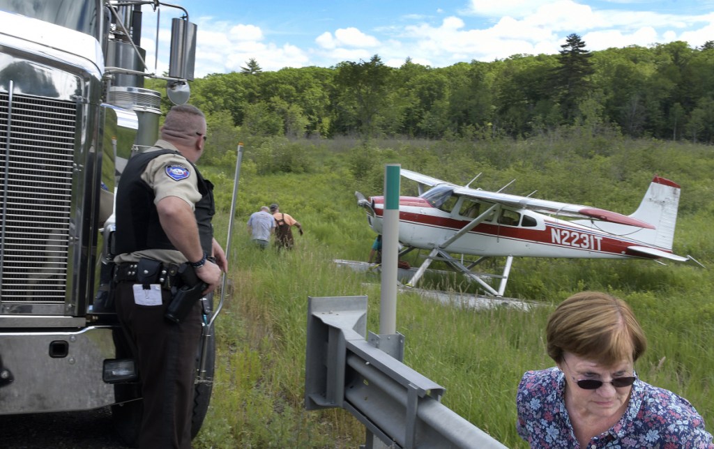 Folks watch a single prop airplane get towed Sunday to Route 126 in Jefferson.