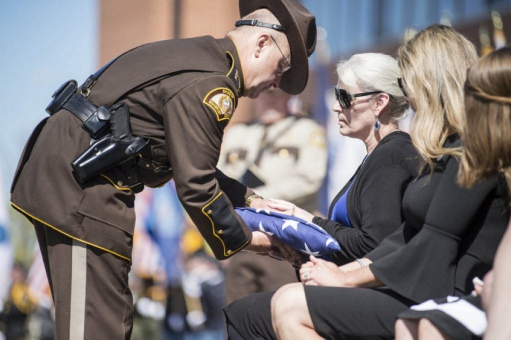 Somerset County Sheriff Dale Lancaster offers a folded American flag to Sheryl Cole, wife of Cpl. Eugene Cole, on May 7 during Cpl. Col's funeral at the Cross Insurance Center in Bangor.