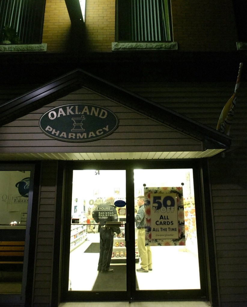 A police officer talks to a person inside The Oakland Pharmacy on Main Street as part of the investigation of a robbery that occurred there on Oct. 31, 2007.