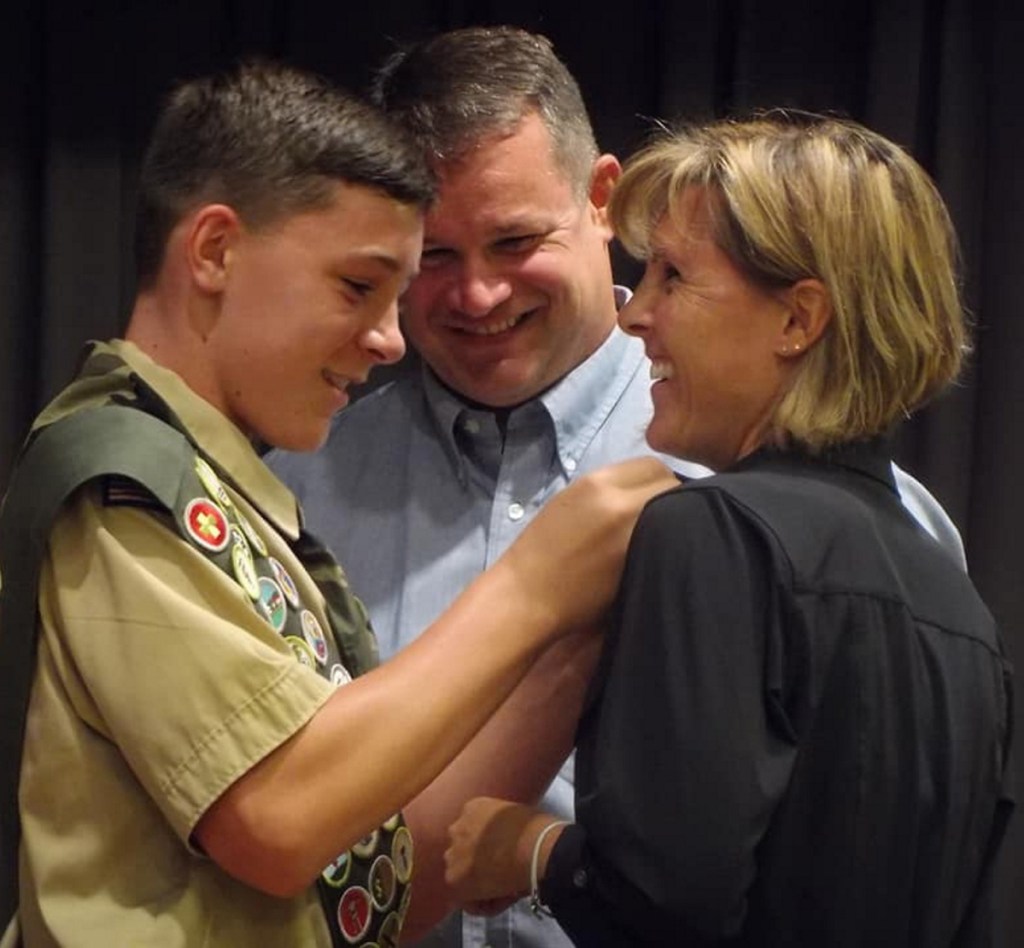 Parker Desjardins presents Stephanie Desjardins with the Mother's Pin in recognition of her support over the years while his father Jeffrey Desjardins watches.