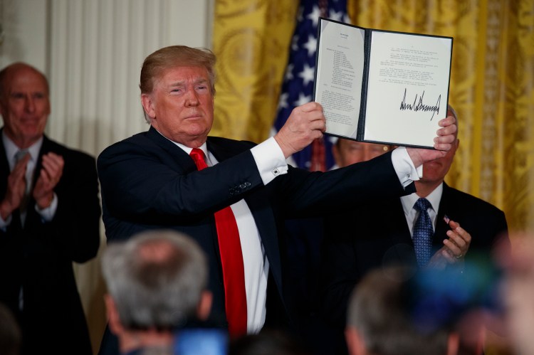 President Donald Trump shows off a "Space Policy Directive" after signing it Monday during a meeting of the National Space Council in the East Room of the White House.