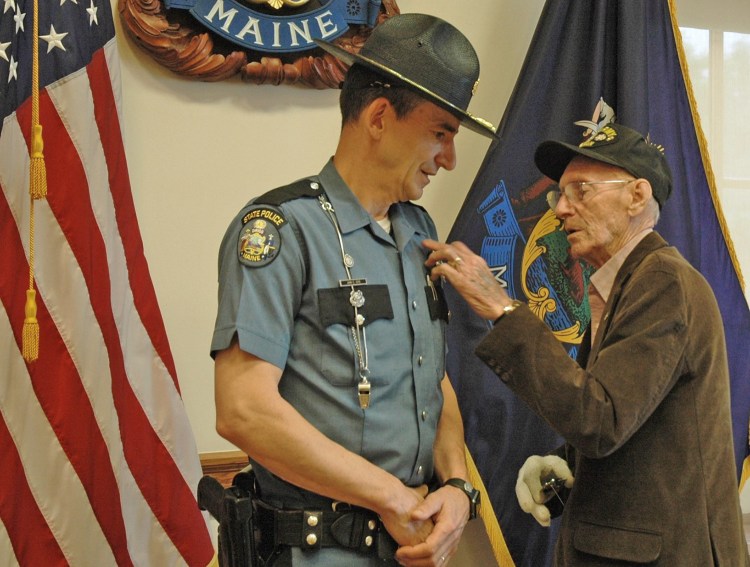 Morris Cote, of Houlton, pins the badge on his son, John Cote, of China, at John Cote's swearing in as the chief of the Maine State Police on Monday in Augusta.  