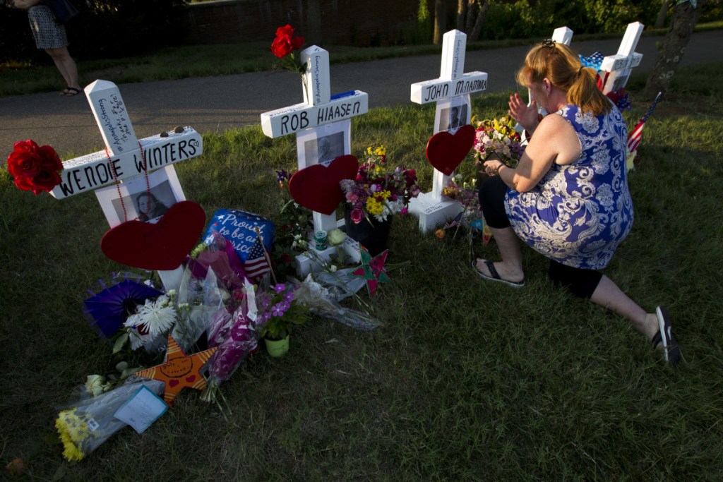Colleen Joseph prays over the crosses at a makeshift memorial at the scene outside The Capital Gazette newspaper in Annapolis, Md., on Sunday. Jarrod Ramos is charged with murder after police say he opened fire Thursday at the newspaper.