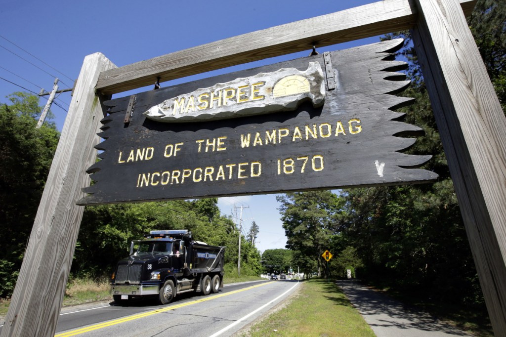 In this Monday, June 25, 2018 photo a wooden sign advises motorists of the location of Mashpee Wampanoag Tribal lands in Massachusetts. The Mashpee Wampanoag Tribe says an unfavorable decision from the U.S. Interior Department on its tribal reservation status would effectively shut down certain government operations, including the tribe's new court system and police force. (AP Photo/Steven Senne)