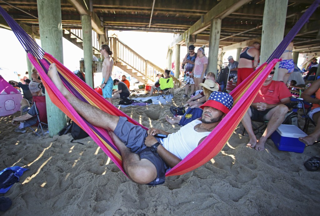 Antonio Seda, of Southbridge, Massachusetts, relaxes in a hammock he hung up under the pier at Old Orchard Beach on Wednesday, when Portland set a new record for the high temperature, hitting 93 degrees.