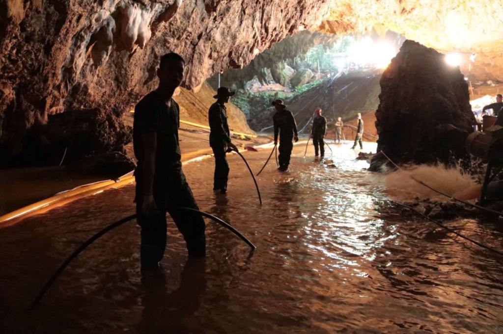 Rescue teams arrange a water pumping system at the entrance of a flooded cave, where 12 boys and their soccer coach had been trapped since June 23, in Mae Sai, Chiang Rai province, northern Thailand. Expert divers extracted four boys on Sunday.
