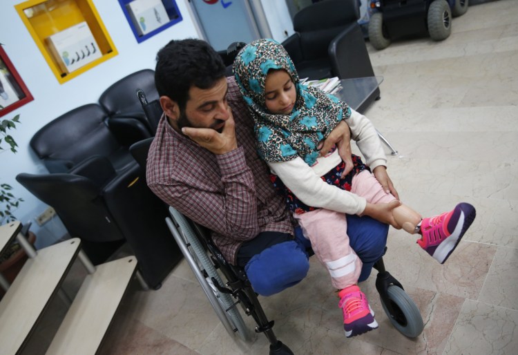 Maya Meri adjusts her prosthetic leg as she sits on her father Mohammed's lap at a rehabilitation clinic in Istanbul. Maya, an 8-year-old girl from war-torn Syria who was born without legs, has been in the spotlight since images of her plight hit social media last month. Her father had made substitute legs for her from tuna cans, plastic tubes and fabric.