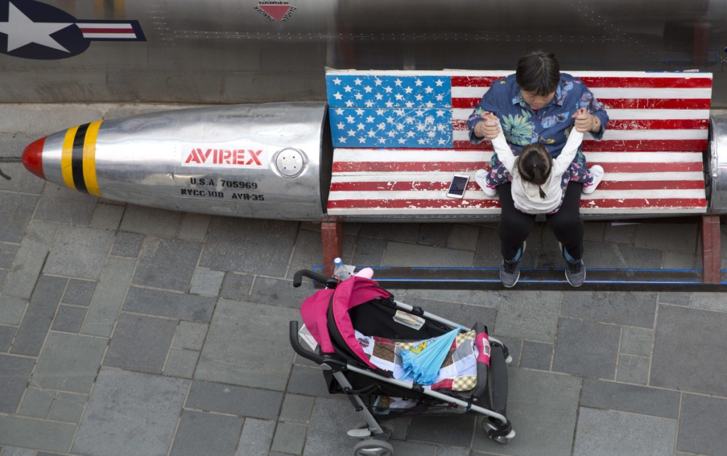 A woman tends to a child near a promotional gimmick in the form of a bomb and the American flag outside a U.S. apparel shop in Beijing. One of China's options in a trade war is to make operating difficult for U.S. companies there.