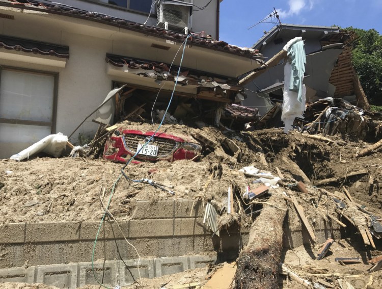 A car is covered with mud as houses are damaged after a mudslide caused by heavy rains in Hiroshima.