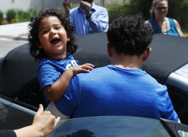 Ever Reyes Mejia, of Honduras, carries his son to a vehicle after being reunited and released by United States Immigration and Customs Enforcement in Grand Rapids, Mich., on Tuesday. Two boys and a girl who had been in temporary foster care in Grand Rapids were reunited with their Honduran fathers after they were separated at the U.S.-Mexico border about three months ago.