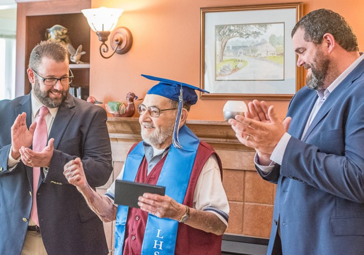 Hospice volunteer Leo Savard, 86, pumps his fist Thursday after getting his Lewiston High School diploma. Presenting the diploma are Assistant Principal Jay Dufour, left, and Principal Jake Langlais.