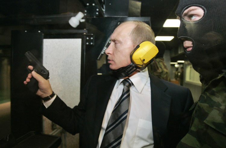 Russian President Vladimir Putin wears headphones as he tests a pistol in a shooting range at the Defense Ministry's Main Intelligence Directorate in Moscow.