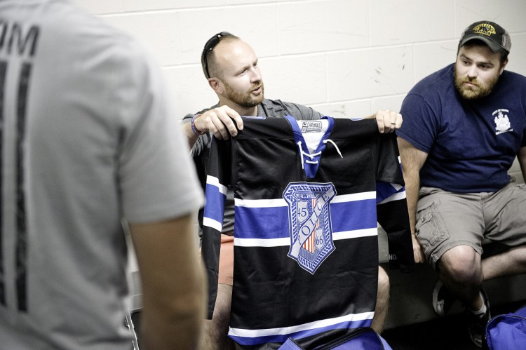 Lewiston police Officers Charlie Weaver, left, and Tyler Michaud look at the new hockey jerseys that the Lewiston Police Department hockey team wore during the game.