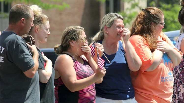 Civilians gather along Main Street in Weymouth, Mass., as the body of Weymouth police Officer Michael Chesna is driven to the medical examiner's office in Boston. Chesna and a bystander died Sunday from bullet wounds.