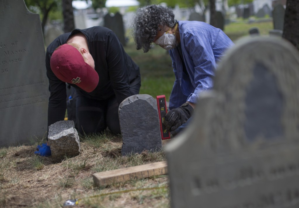 PORTLAND, ME - JULY 14: Eastern Cemetery in Portland is celebrating 350 years. Sarah Whitmore, left, and Diane Brakeley, members of Spirits Alive, a nonprofit group formed 11 years ago to restore and preserve the cemetery, set a footstone belonging to the grave of George McDowell on Saturday, July 14, 2018, after it was recently recovered near the "dead house". (Photo by Derek Davis/Staff Photographer)